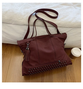 Detail of vintage burgundy tote bag with silver studs and tassel charm decoration