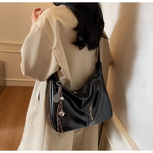 Rear view of a model wearing a glossy black hobo tote bag with a tennis racket charm