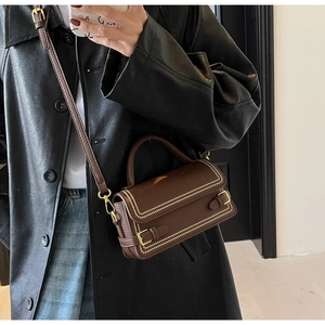 Close-up of brown textured leather crossbody bag with gold rivets and metallic details