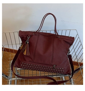 Detail view of burgundy tote bag with silver rivets and leather tassel in a shopping cart