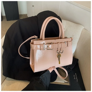 Detail of pink patent leather handbag with gold key charm and crossbody strap