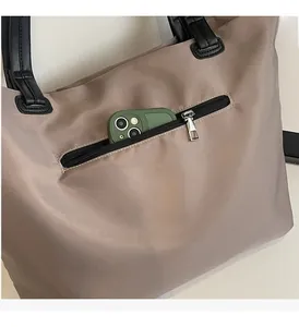 Gros plan sur la poche zippée avant d'un sac en nylon beige contenant un smartphone