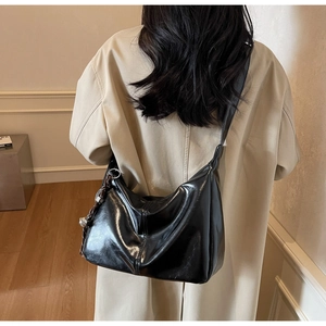Detailed back view of a black glossy hobo bag with wide strap on a model outfit