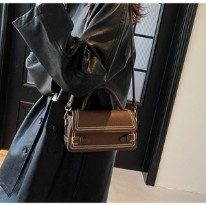Detail of dark brown lychee leather handbag with vintage metal buckles and stitching