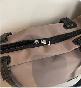 Gros plan sur la fermeture éclair en métal argenté et le tissu en nylon d'un sac de voyage brun