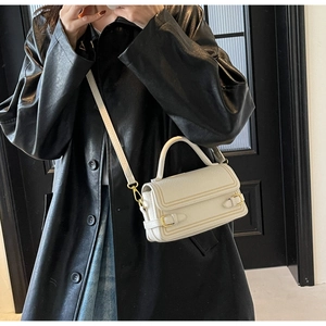 Close-up of white lychee-pattern leather bag with golden square buckle detail