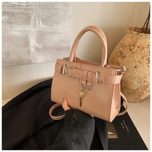 Close-up of pink glossy handbag with metal buckle strap and fashion key pendant
