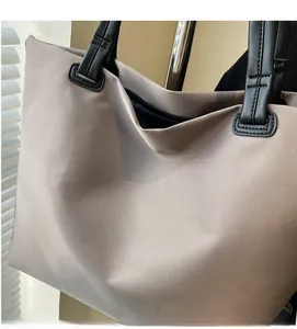 Gros plan sur un sac cabas en nylon marron clair avec des poignées en cuir noir durables