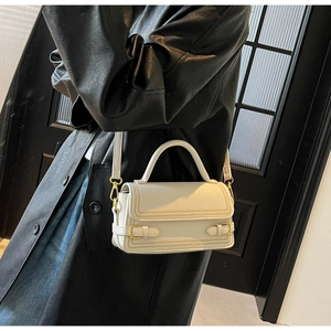 Close-up of white lychee pattern leather handbag with gold metal buckles and crossbody strap