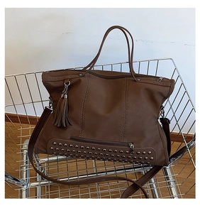 Detail view of brown vintage tote bag with metal rivets and tassel in shopping cart