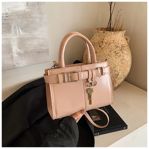 Detail of nude pink square handbag with gold key pendant in a premium lifestyle setting