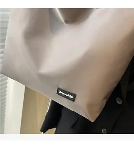 Gros plan d'un grand sac fourre-tout kaki montrant le tissu en nylon et le logo de marque