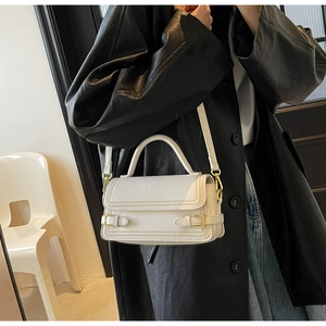 Close-up of white lychee pattern leather handbag featuring elegant gold metal buckles