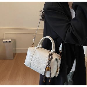 White faux leather crossbody bag with embossed letters and a tassel bell charm
