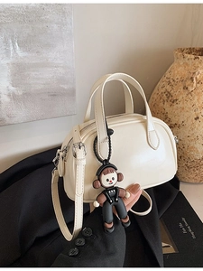 Cremeweiße Boston-Handtasche aus Kunstleder mit Schultergurt und Puppenanhänger