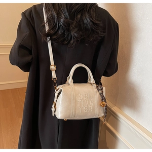 Detail of cream leather handbag with embossed CULTIVATOR logo and polka dot scarf charm