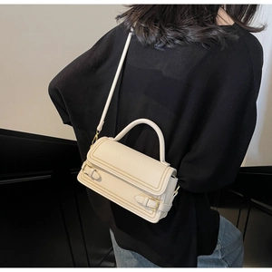 Detail view of white leather crossbody bag with golden beaded edges and top handle