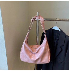 Detail shot of a pink hobo bag featuring wide knotted straps and metallic zipper closure