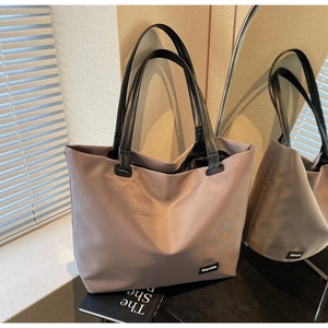 Gros plan du sac fourre-tout gris imperméable avec anses noires et étiquette tissée
