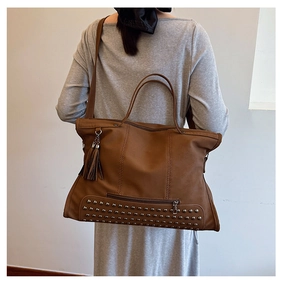 Detailed back view of a brown vintage tote bag with silver studs and tassel charm