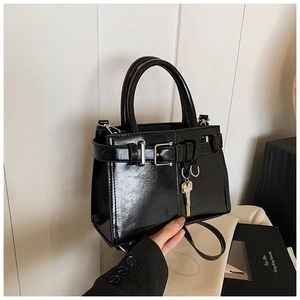 Detail of black patent leather handbag with silver buckle and golden key charm decoration