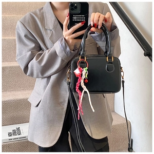 Chic black boston handbag with golden hardware and colorful tassel on model