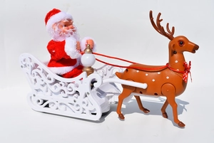 Detail of Santa Claus in velvet suit on white sleigh pulled by a reindeer toy