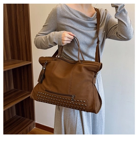 Detail of vintage brown tote bag with metal rivets, leather tassels, and adjustable strap
