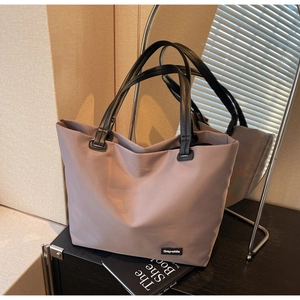 Détail du sac de voyage imperméable rose-gris avec anses en cuir noir et étiquette de marque
