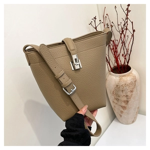 Detailed view of khaki lychee leather bucket bag with silver metal lock and strap