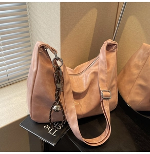 Close-up of pink leather hobo bag featuring silver hardware and a decorative charm