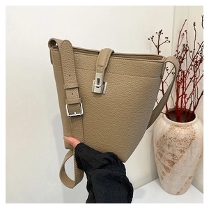 Detail of lychee pattern leather bucket bag with silver metal swivel lock and strap