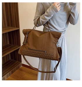 Detail of vintage brown tote bag with silver studs, tassels and crossbody strap