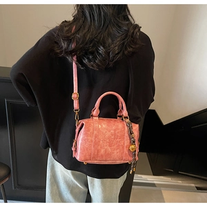 Pink vintage PU leather Boston bag shown on model featuring letter embossing and tassel