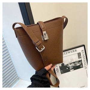 Close-up of brown lychee pattern leather bucket bag with silver buckle and shoulder strap