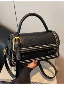 Minimalist black pebbled leather handbag with gold studs and adjustable shoulder strap