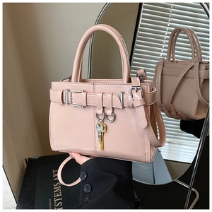 Detail of dusty pink tote bag with metallic key charms and adjustable shoulder strap