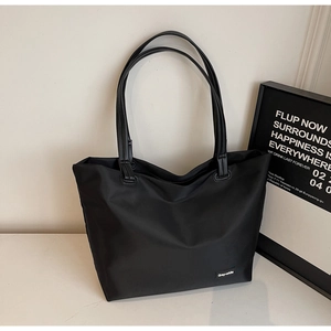 Détail d'un grand sac de voyage noir avec étiquette carrée en tissu de la marque