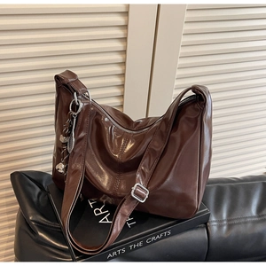 Detail of glossy brown leather tote featuring silver hardware and adjustable strap
