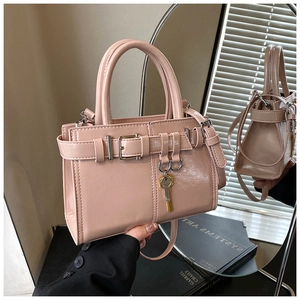 Detailed close-up of glossy pink patent leather handbag with a gold key charm