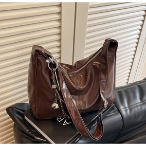 Detailed close-up of dark coffee tote bag featuring glossy leather and silver bell charm
