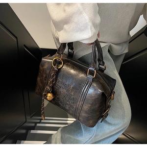 Detail of dark brown vintage Boston bag with textured leather and gold hardware