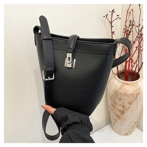 Detail of black lychee grain leather bucket bag with silver metal H-lock and adjustable strap
