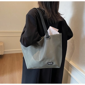 Détail d'un grand sac de voyage vert olive avec anses noires et logo sur le côté