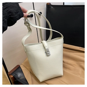 Detailed shot of beige lychee pattern bucket bag with silver metal buckle and wide strap