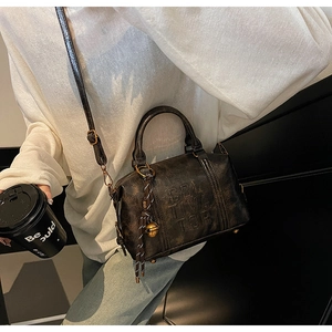 Detail of vintage brown Boston bag with Beltiva embossing and woven bell pendant