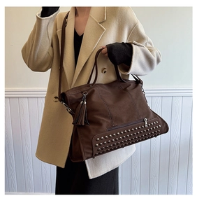 Detail of dark brown matte tote bag featuring silver studs and detachable shoulder strap