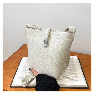 Detail shot of lychee grain cream bucket bag with silver metal clasp and leather texture
