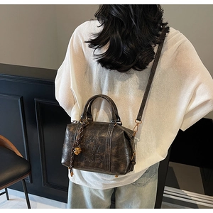 Detail of vintage embossed leather crossbody bag with metal bell charm and adjustable strap