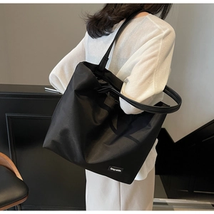Photo lifestyle d'un grand sac de voyage noir avec étiquette Gray-white porté à l'épaule